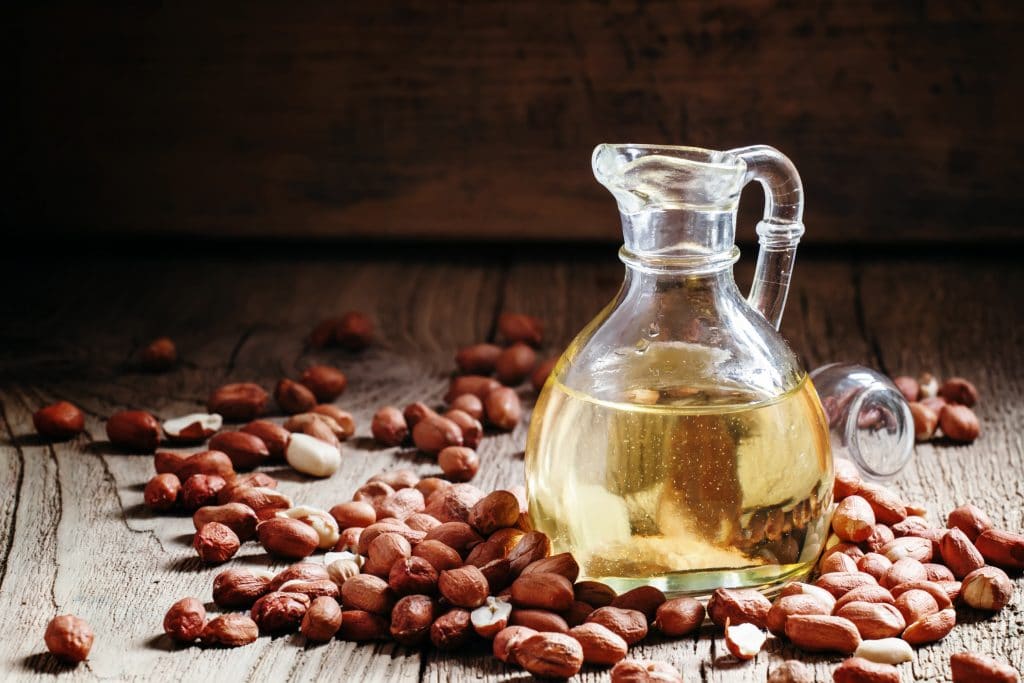 Peanut butter in a glass a Jug and spilled nuts on an old wooden background, selective focus