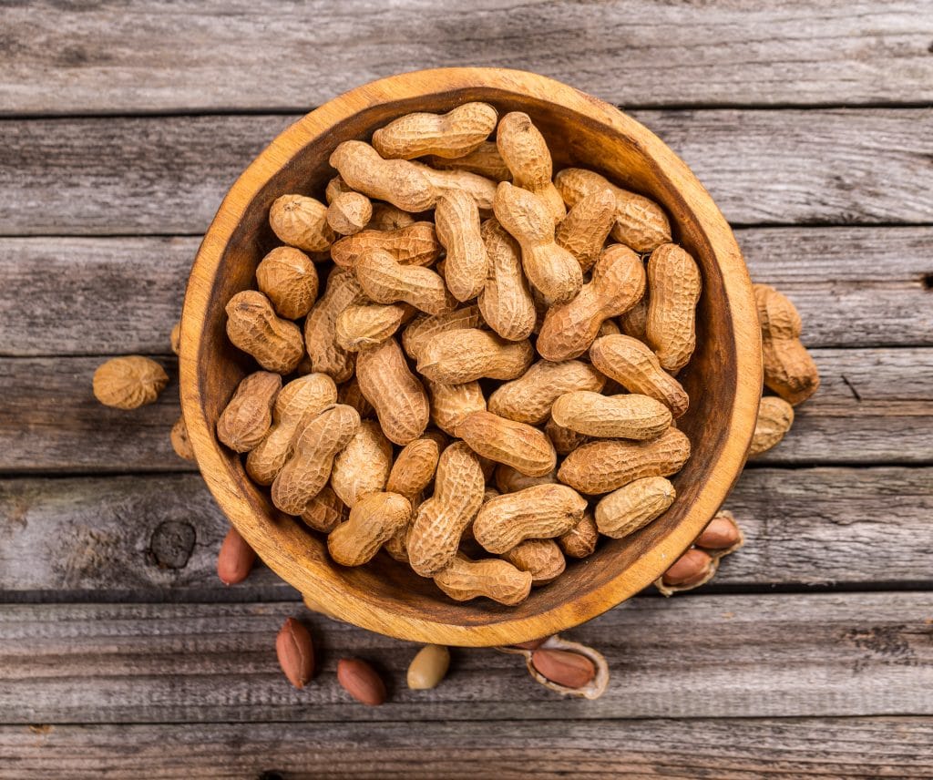 Top view of dried peanuts in wooden bowl