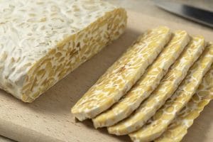 Traditional vegetarian tempeh sliced on a cutting board close up