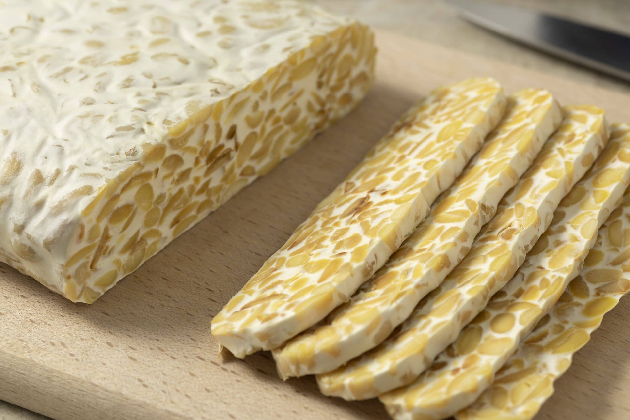Traditional vegetarian tempeh sliced on a cutting board close up