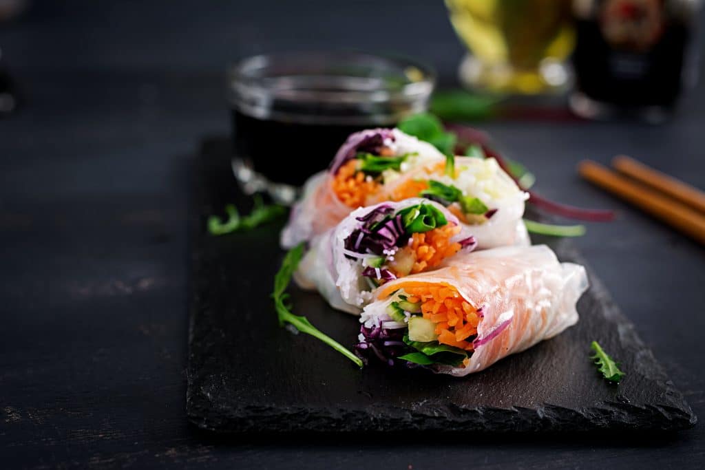 Vegetarian vietnamese spring rolls with spicy sauce, carrot, cucumber, red cabbage and rice noodle. Vegan food. Tasty meal.
