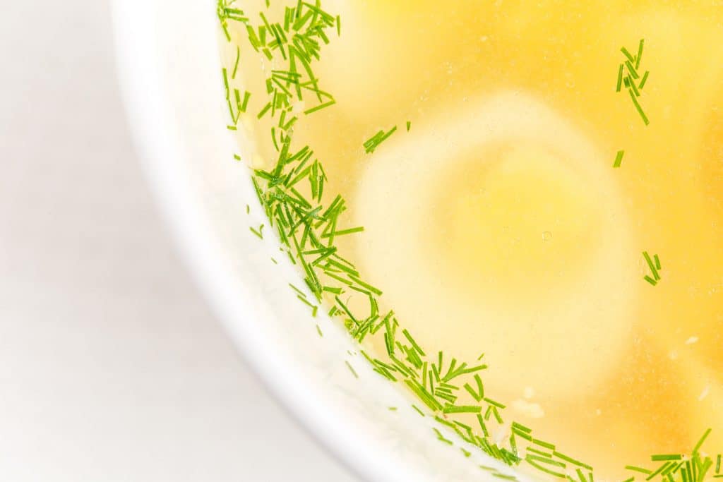 Chicken consomme soup with homemade noodles and quail eggs. Macro. Photo can be used as a whole background.