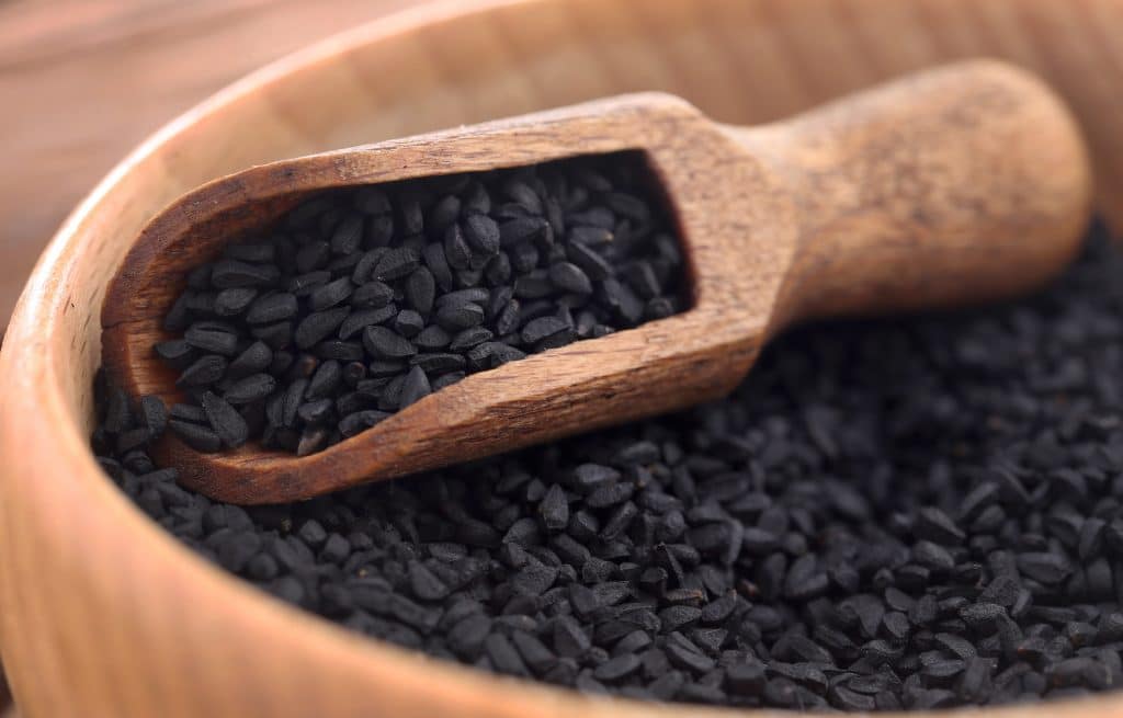 Nigella seeds with wooden scoop in a bowl